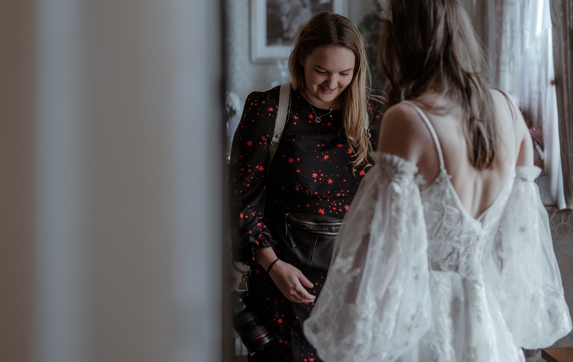 photographer looks down at bride in dress and smiles