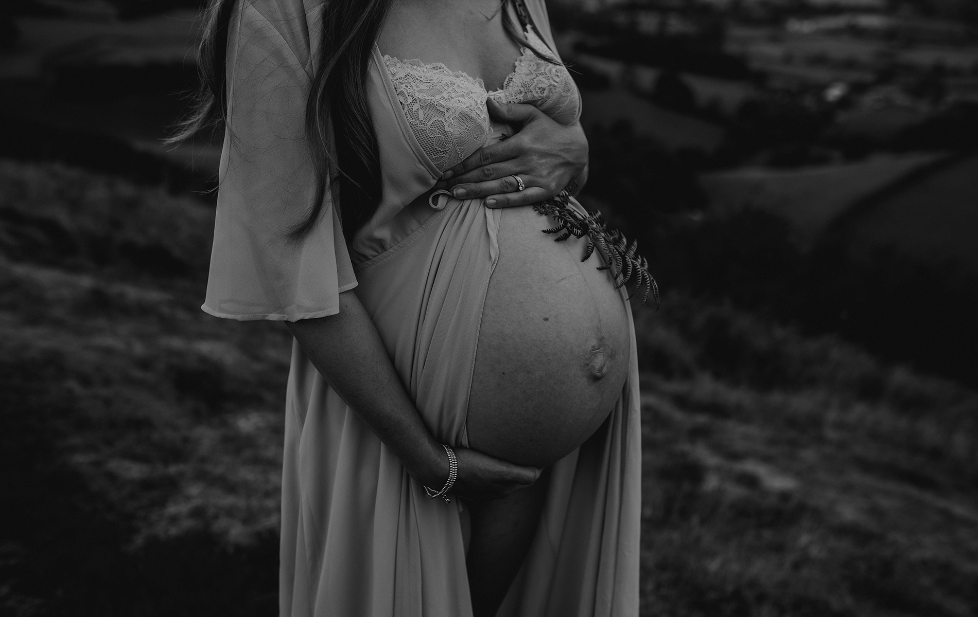 black and white image of baby bump infront of rolling hills