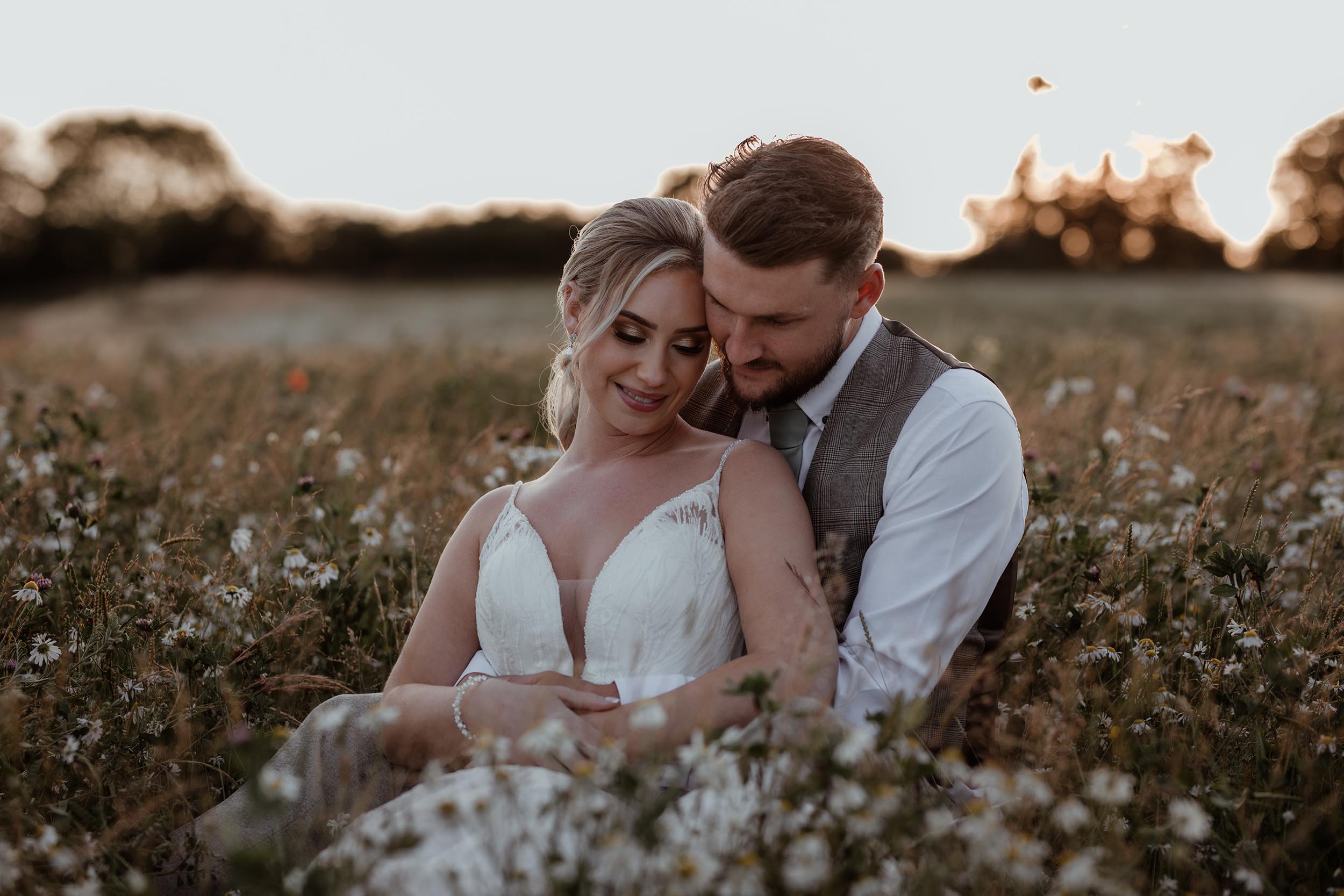 bride and groom hug in daisy field at golden hour at Crockwell Farm wedding